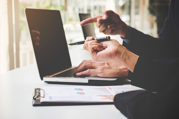 Donna di affari che lavora al suo caffè e usando il computer portatile, discutendo le tabelle e grafici mostrando i risultati del loro successo.