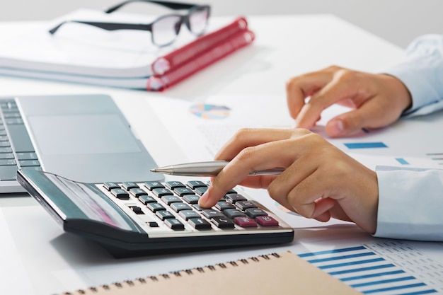 Donna di affari che lavora allo scrittorio facendo uso del calcolatore che analizza contabilità di finanza nell'ufficio
