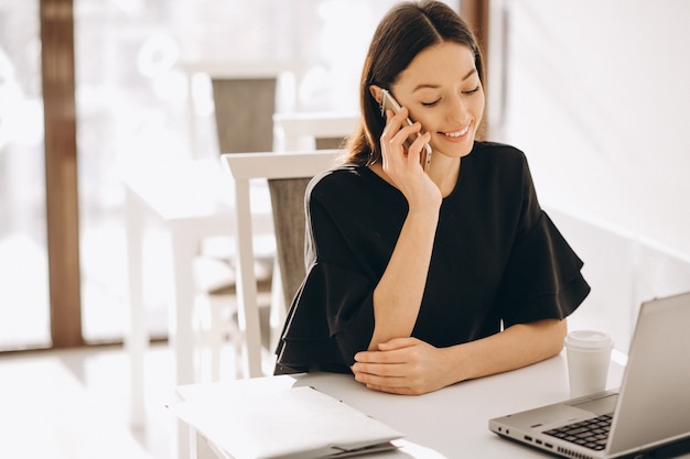 Donna di affari che lavora con il computer portatile in un caffè bianco