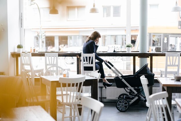 Donna di affari che lavora dal caffè con la carrozzina dalla sua parte