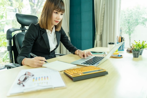 Donna di affari che lavora nell&#39;ufficio con i documenti di carta e del computer portatile sullo scrittorio