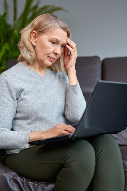 Donna di affari che lavora seduta online su un divano in un ufficio.