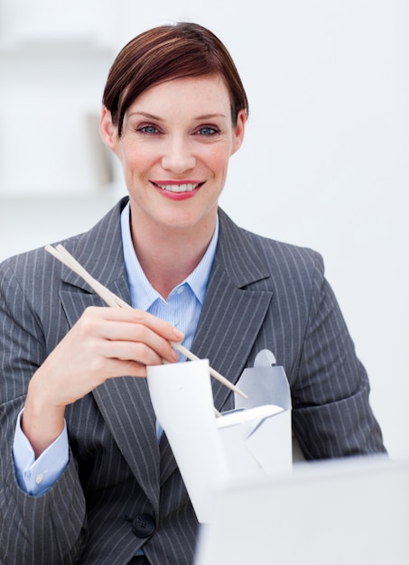 Donna di affari che mangia cibo cinese sul lavoro