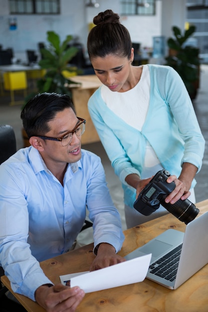 Donna di affari che mostra macchina fotografica digitale al collega