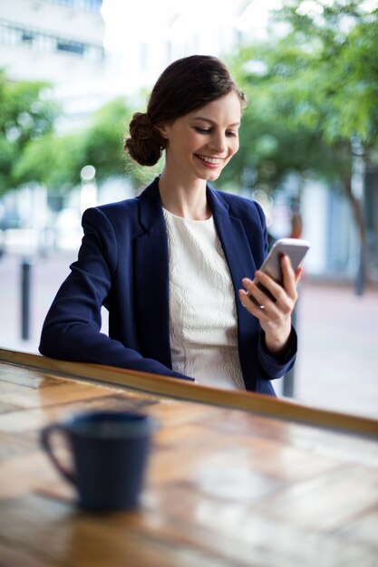 Donna di affari che per mezzo del telefono cellulare al contatore