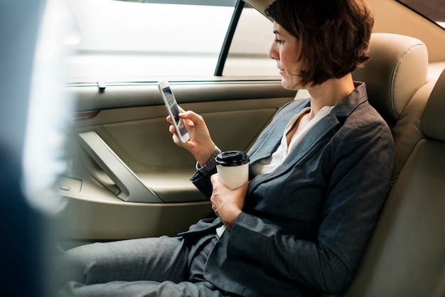 Donna di affari che per mezzo dell&#39;automobile dello Smart Phone dentro