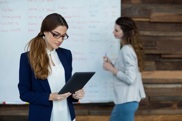 Donna di affari che per mezzo della compressa digitale mentre lavoro del collega