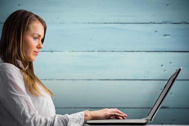 Donna di affari che scrive sul suo computer portatile contro tavole di legno dipinte di blu