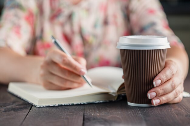 Donna di affari che si siede con una tazza di caffè contro