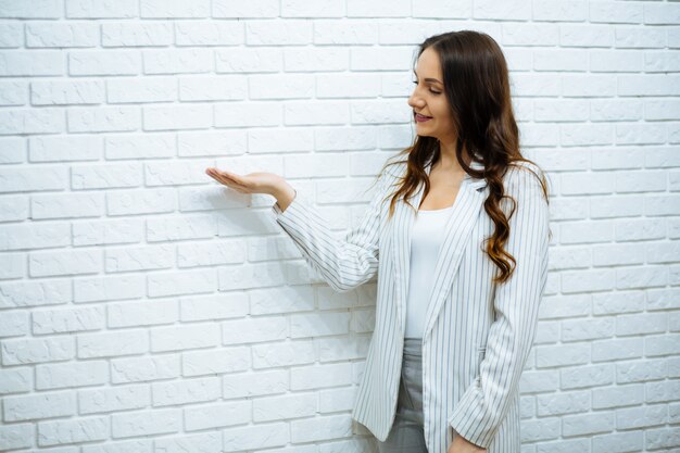 Donna di affari che sta vicino al muro di mattoni bianco