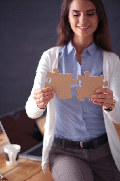 Donna di affari che tiene e che indica un pezzo del puzzle Puzzle della donna della squadra di concetto