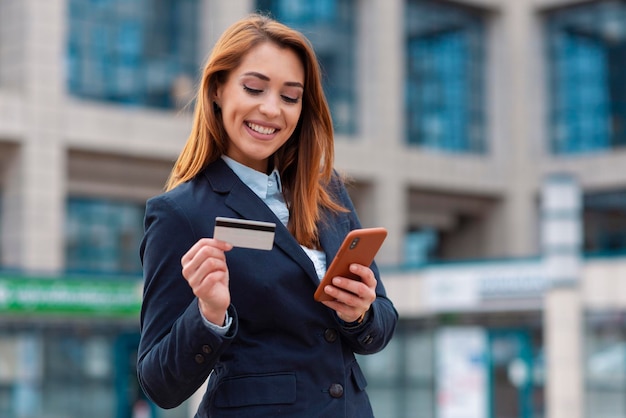 Donna di affari che tiene telefono e utilizza la carta di credito