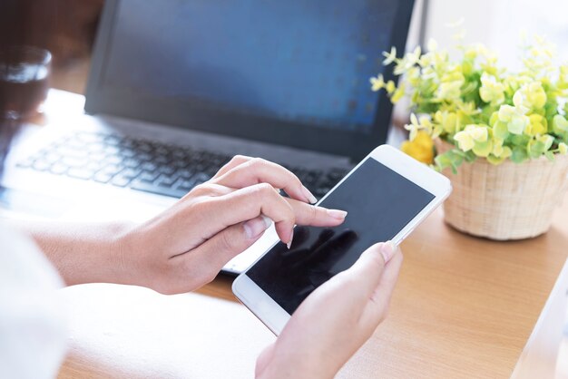 Donna di affari che utilizza cellulare con il computer portatile su fondo