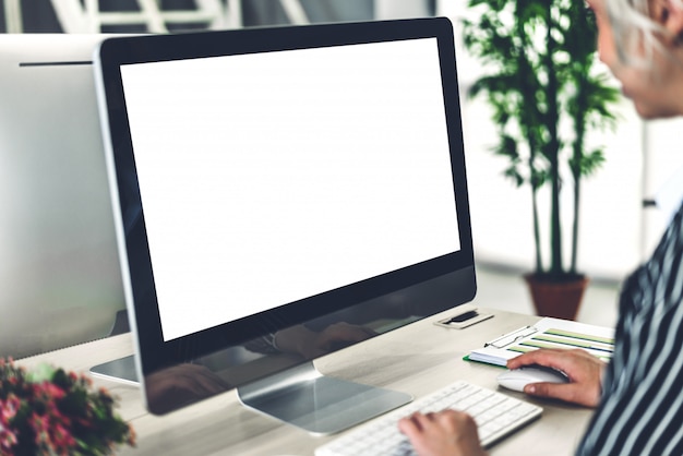 Donna di affari che utilizza computer con gli schermi in bianco del modello bianco nel sottotetto del lavoro moderno