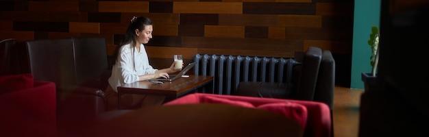Donna di affari con il computer portatile. Sta lavorando e si rilassa in un bar bevendo latte