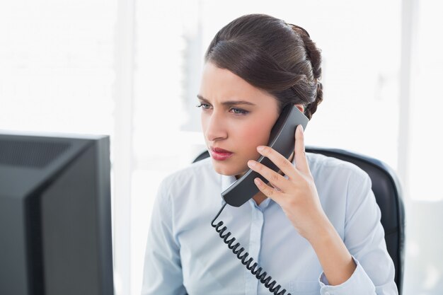 Donna di affari dai capelli marrone di classe severa che risponde al telefono