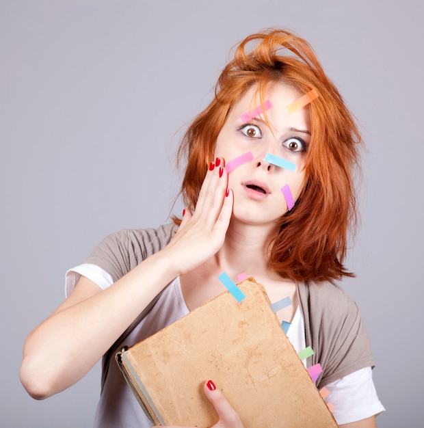 Donna di affari dai capelli rossi con libro e note sul viso.