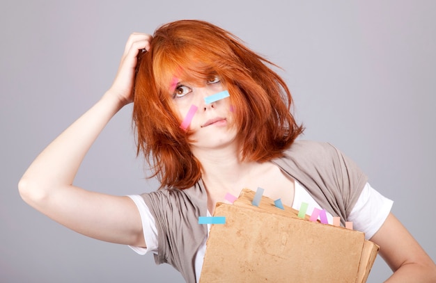 Donna di affari dai capelli rossi con libro e note sul viso.