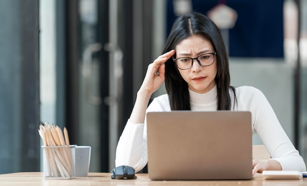 Donna di affari esausta Donna che lavora al computer portatile con mal di testa