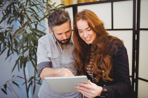 Donna di affari felice con il collega che per mezzo della compressa digitale