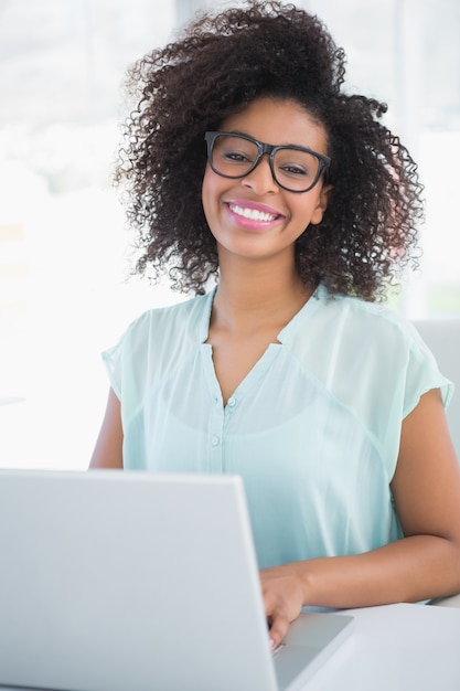 Donna di affari felice dei pantaloni a vita bassa che lavora al computer portatile