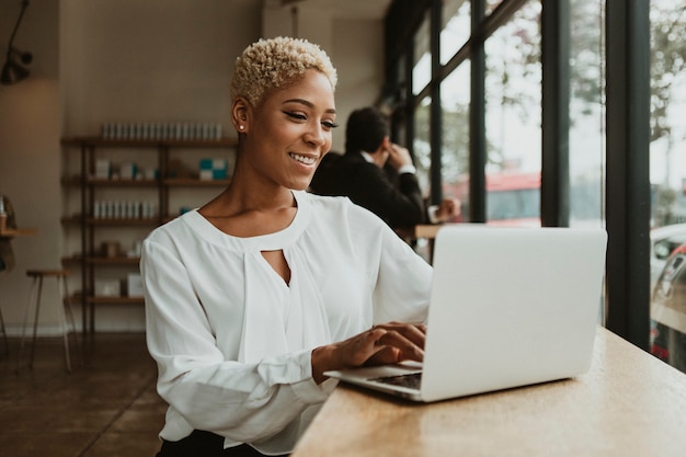 Donna di affari felice in un caffè usando il suo computer portatile