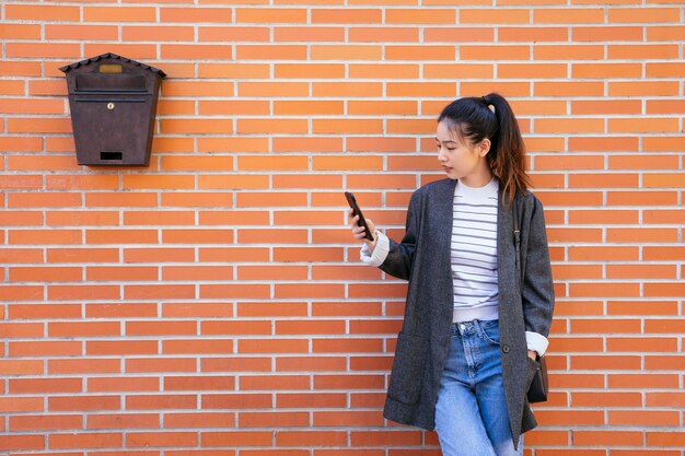 Donna di affari felice nelle vie facendo uso dello smartphone