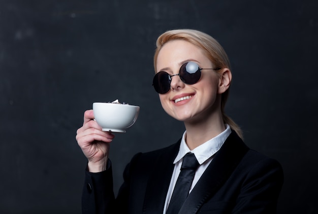 Donna di affari in occhiali da sole con la tazza di caffè