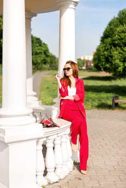 Donna di affari in un vestito rosso vicino ad un gazebo bianco