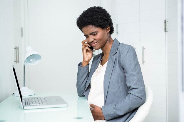 Donna di affari incinta sul telefono nell&#39;ufficio