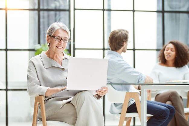 Donna di affari matura che utilizza un computer portatile sul posto di lavoro