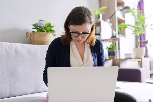 Donna di affari matura con il computer portatile che lavora a distanza a casa. Libero professionista, comunicazione online, consulenza, formazione, business. Tecnologia, concetto di stile di vita a distanza