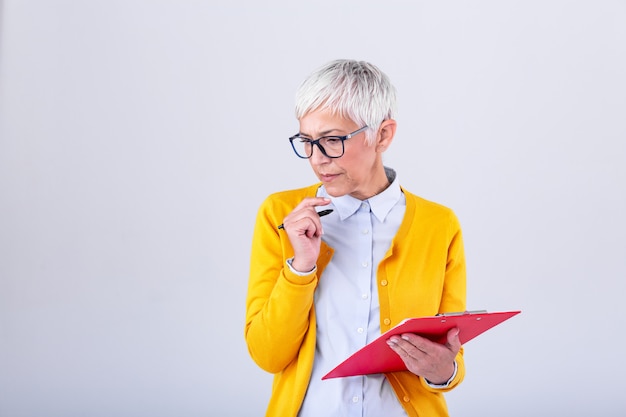 Donna di affari matura nell'usura convenzionale che pensa all'offerta di lavoro prima della firma dei documenti. Appunti della holding della donna di affari. Lavagna per appunti moderna e laboriosa della tenuta della donna in mani