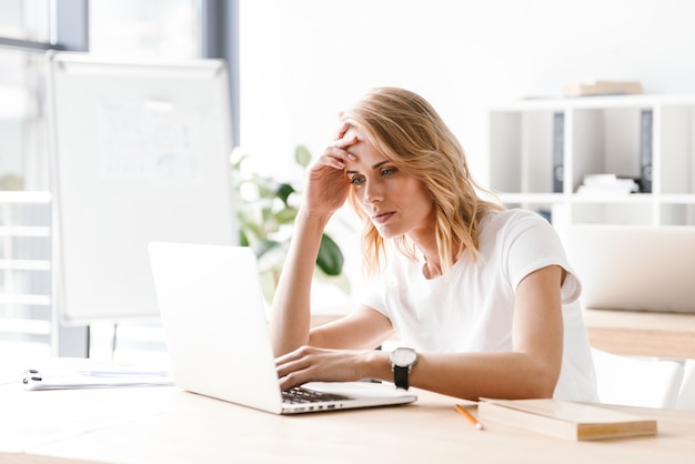 Donna di affari messa a fuoco che lavora al computer portatile