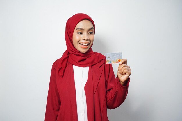 Donna di affari musulmana asiatica in rosso casual in possesso di una carta di credito isolata da sfondo bianco