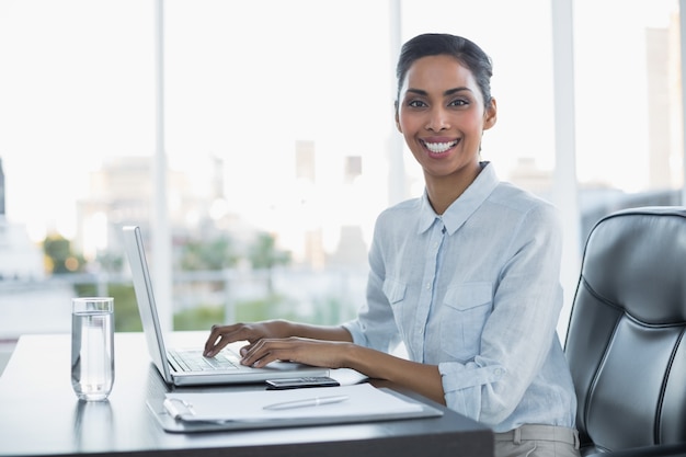 Donna di affari sorridente allegra che lavora al suo computer portatile