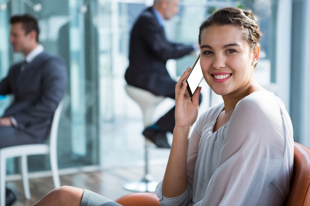 Donna di affari sorridente che parla sul telefono cellulare in ufficio