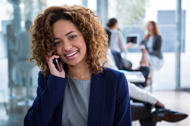 Donna di affari sorridente che parla sul telefono cellulare in ufficio