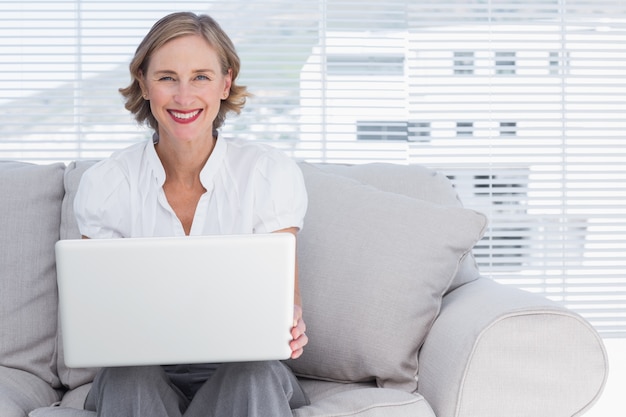 Donna di affari sorridente che per mezzo di un computer portatile