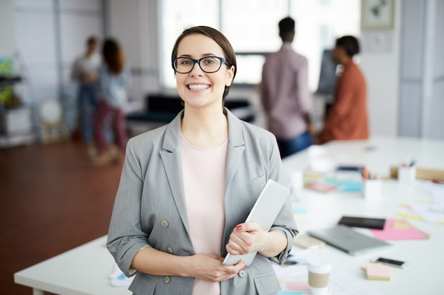 Donna di affari sorridente che posa nell'ufficio