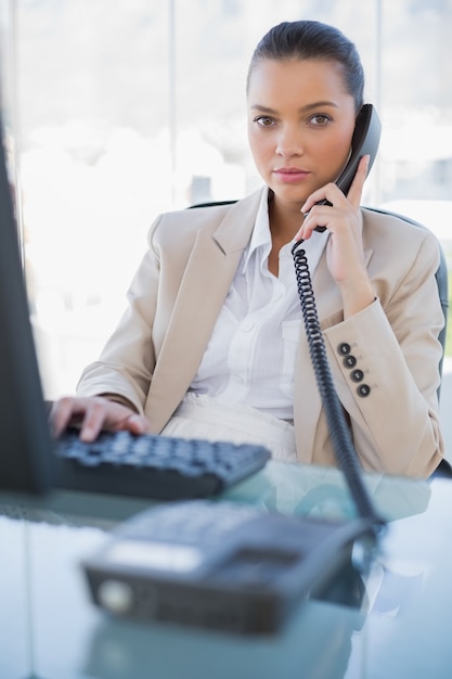 Donna di affari splendida seria che risponde al telefono