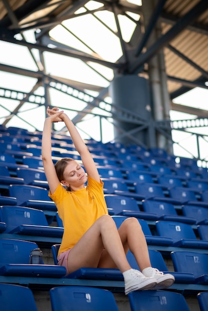 Donna di angolo basso che si siede sulla tribuna