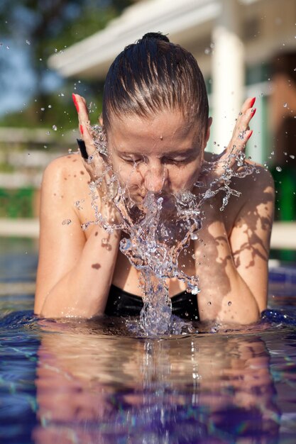 Donna di bellezza che si lava il viso con l'acqua