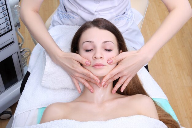Donna di bellezza con massaggio cosmetico, trattamento viso, primi piani.