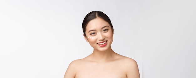 Donna di bellezza di cura della pelle Bellezza donna sorridente applicando crema Ritratto di bellezza del modello femminile caucasica asiatica bella isolata on white