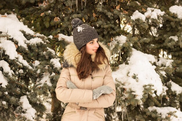 Donna di bellezza nel parco in cappello caldo con l'albero dietro