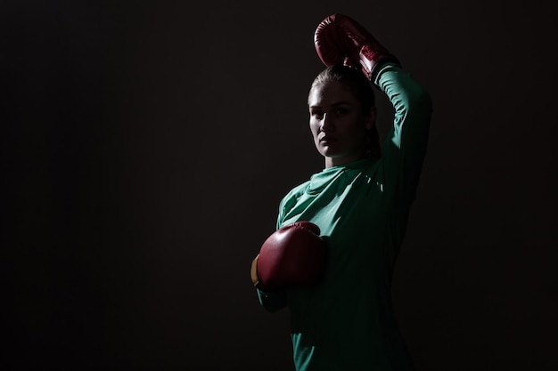 Donna di boxe in abbigliamento sportivo verde e guantoni da boxe rossi