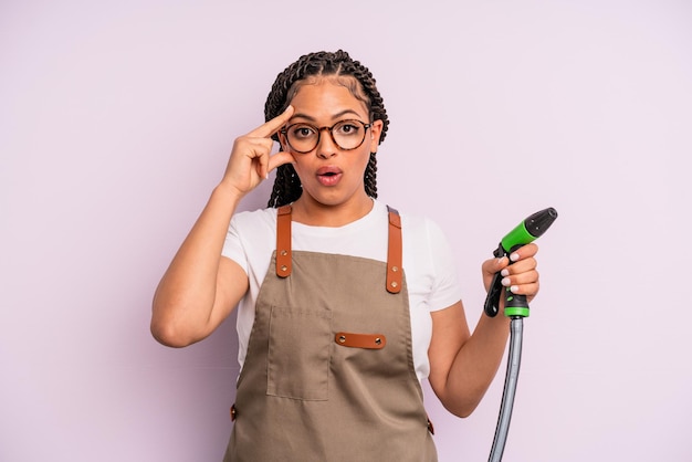 Donna di colore afro che sembra sorpresa, realizzando un nuovo pensiero, idea o concetto. concetto di tubo da giardiniere