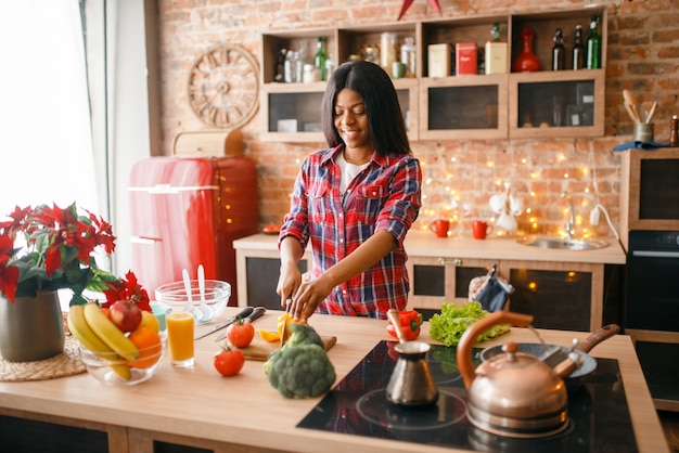Donna di colore che cucina una sana colazione in cucina.