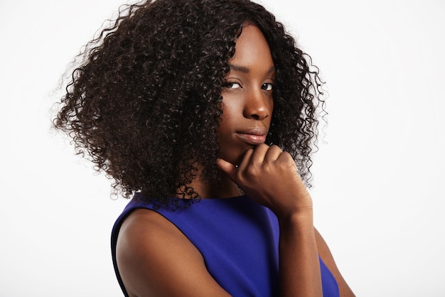 Donna di colore con grandi capelli afro che pensa e guarda alla macchina fotografica